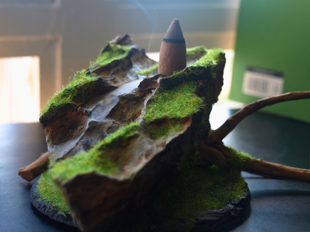Detalle del humo fluyendo por estructura rocosa con musgo verde.