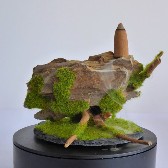 Quemador de incienso de reflujo artesanala hecho con madera, piedra y una base de pizarra, el humo fluye entre los huecos de la piedra creando un efecto de cascada hipnotiznte.